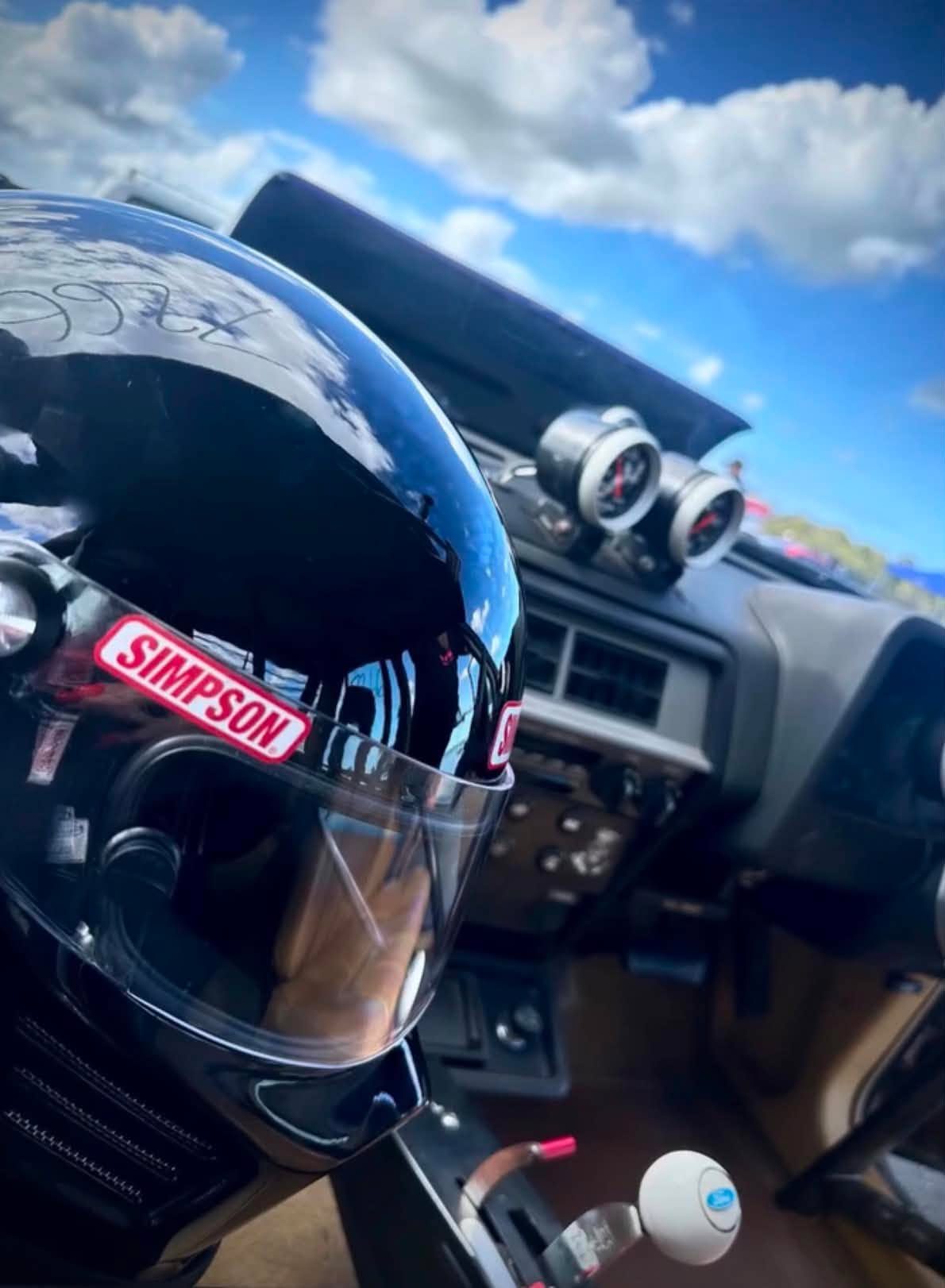 Simpson racing helmet resting on the dash of a car at a track day