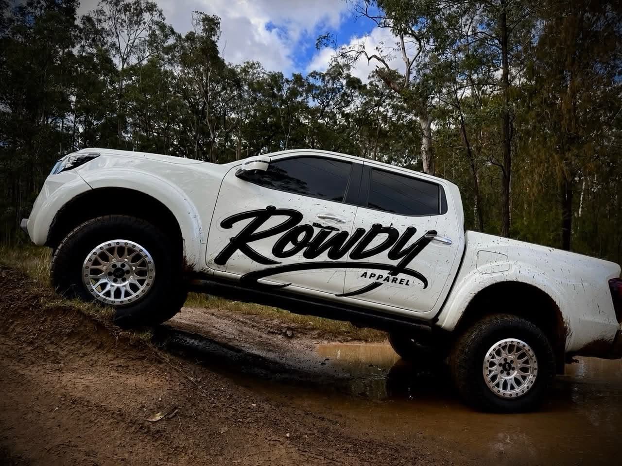 Rowdy Apparel decal along the side of a white ute on a muddy bush track